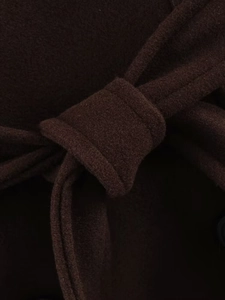 Detail of the adjustable waist belt and premium wool texture on a brown long coat