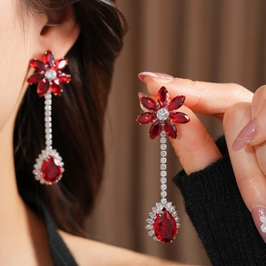 Detailed close-up of red zircon flower and water drop tassel earrings on a model