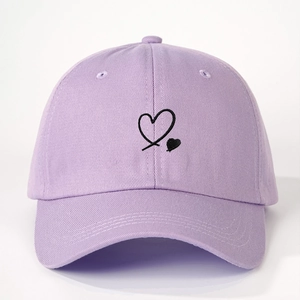 Close-up of a lavender cotton baseball cap featuring a black embroidered heart on the front