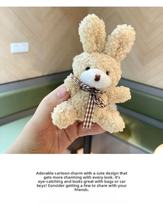 Close-up of a cute plush bunny keychain with a brown plaid bow tie in hand