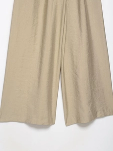 Detailed macro view of wide-leg trousers featuring khaki cotton linen fiber texture