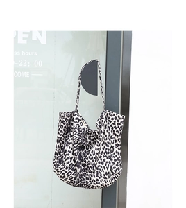 Detail of a large leopard print canvas tote bag hanging on a glass door handle