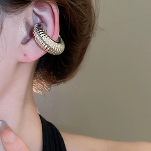 Gros plan d'une boucle d'oreille à clip argentée avec texture torsadée et surface polie