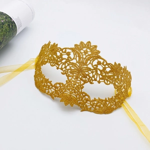 Close-up of golden lace masquerade mask with intricate floral embroidery and satin ribbons