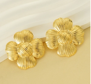Macro view of golden four-leaf clover earrings with detailed metallic texture finish