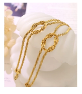 Detailed macro view of gold-plated twisted rope bracelet with a central infinity knot