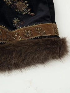 Close-up of black velvet vest with intricate beadwork embroidery and faux fur trim