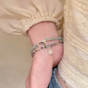 Nahaufnahme von Perlenarmband mit Delphin-Anhänger und Seestern im Urlaubsstil