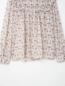 Détail d'une blouse en mousseline fleurie avec volants et poignets de manches longues boutonnés