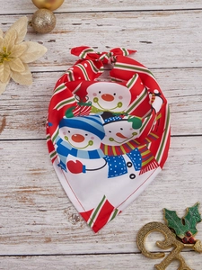 Close-up of a festive Christmas pet bandana with snowman print and red stripes on wood