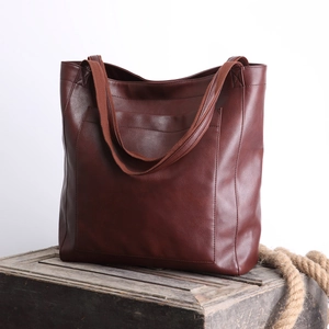 Détail du sac cabas vintage en cuir marron avec poche extérieure et bandoulières en textile