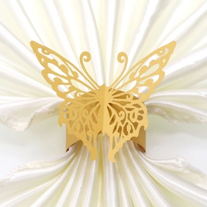 Macro detail of golden laser-cut butterfly napkin ring on white satin background