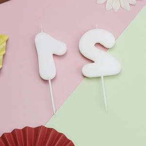 Macro view of white number 1 and 2 birthday candles on a colorful party background