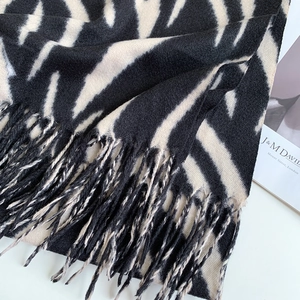 Detailed view of striped zebra pattern knit scarf featuring soft fringe and wool texture