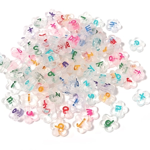 Macro shot of colorful acrylic flower-shaped beads with printed alphabet letters for DIY jewelry