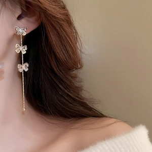 Vue détaillée des boucles d'oreilles nœuds dorés avec glands en zircone sur un mannequin