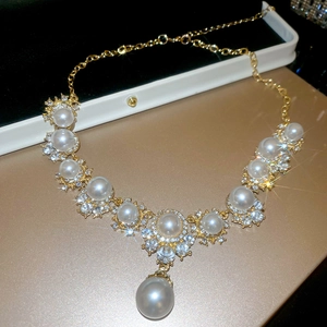 Close-up of gold pearl pendant necklace with crystals in premium white jewelry box