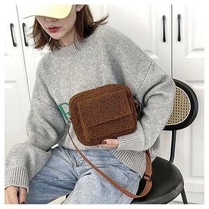 Brown sherpa crossbody bag shown as a shoulder carry style on a sitting model