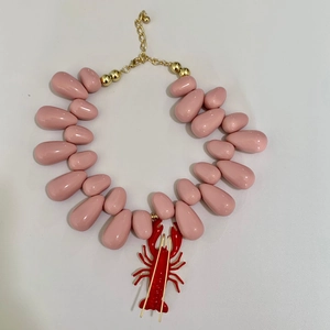 Detail of pink teardrop beads and red lobster pendant on a golden chain necklace