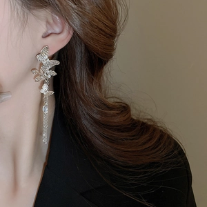 Close-up of silver butterfly tassel earrings with crystals on a model in a black suit