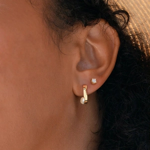 On-ear detail of golden square hoop earring with pearl and matching crystal stud