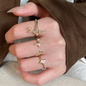 Close-up of three gold starburst rings with zircon stones worn on fingers in a trendy style
