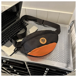 Detail of oxford cross-body bag featuring orange accents and adjustable buckle strap