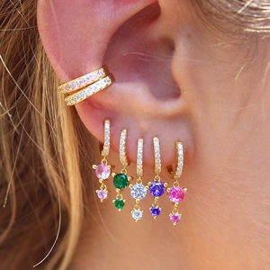 Detailed close-up of colorful crystal hoop earrings with pavé zircons on a model