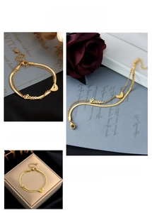 Detail of gold double-layer chain bracelet with Love lettering and heart pendant