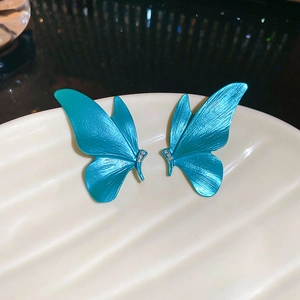 Detailed macro view of blue butterfly earrings with sparkling cubic zirconia on a beige plate