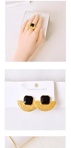 Detail of gold fan-shaped necklace and earrings set with black square gemstones