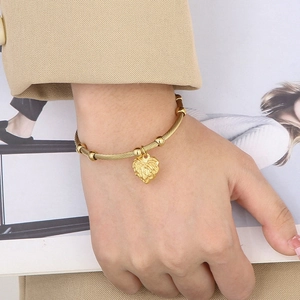 Gold stainless steel twisted wire cuff bracelet featuring a textured heart pendant charm