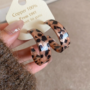 Macro detail of acrylic leopard print C-shaped hoop earrings with retro tortoiseshell pattern