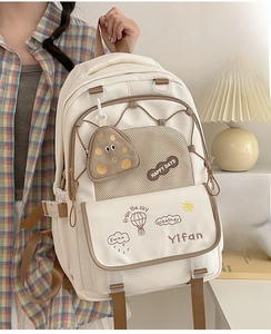 Detail of white nylon backpack with brown embroidery and small round coin purse accessory