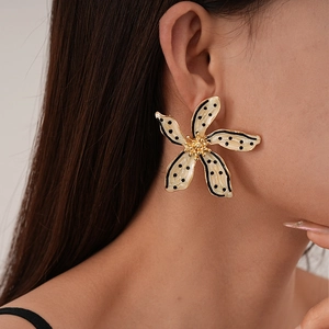 Boucles d'oreilles fleurs rétro à pois noirs et bordure dorée portées par un mannequin