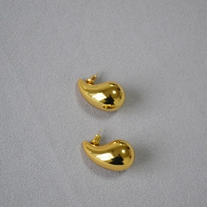 Detailed close-up of chunky gold teardrop earrings with a high-polished mirror finish