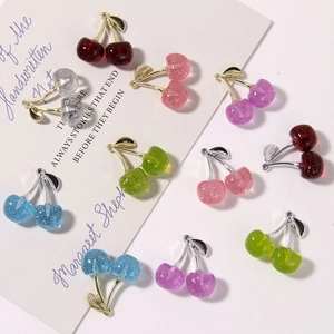Detail of DIY glitter resin cherry charms with metal leaves and rings for jewelry