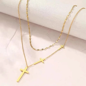 Detail of 18K gold double-layer necklace featuring three minimalist cross pendants