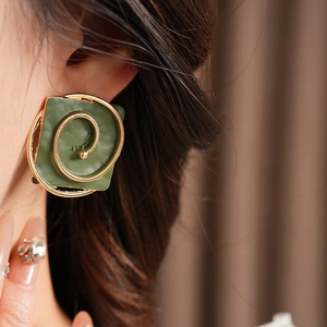 Close-up of vintage square spiral earring in dark green and gold on a model's ear