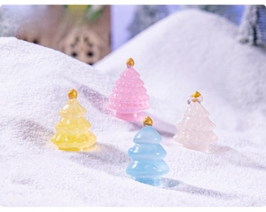 Miniature resin Christmas trees in pastel colors with gold beads on snowy landscape
