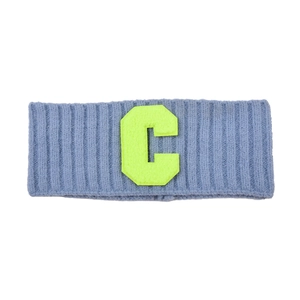 Détail d'un bandeau en maille gris-bleu avec broderie de la lettre C jaune néon