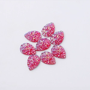 Close-up of teardrop resin jewelry charms in hot pink with glittering texture finish