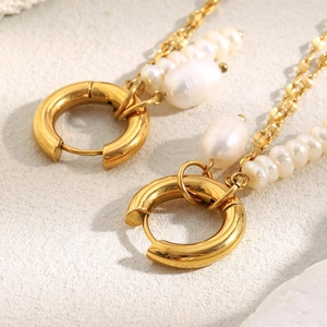 Detailed macro view of 18K gold plated steel earrings with dangling white pearl chains