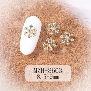 Detail of 8.5x9mm gold snowflake nail charms with rhinestones on a white mannequin nail
