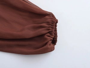 Dettaglio dell'abito in chiffon bohémien con polsini elastici marroni e trama velata