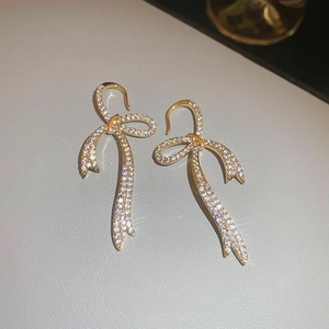 Detail of bow-shaped earrings with gold plating and sparkling pavé set cubic zirconia