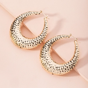 Detailed view of large gold-tone C-shaped hoop earrings with a unique hammered texture finish