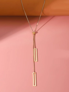 Detail of a gold geometric Y-necklace with two rectangular hollow pendant charms