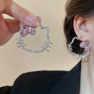 Dettaglio dell'orecchino a forma di gatto in argento traforato con fiocco di cristallo rosa