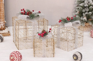 Detailed view of three gold wire Christmas gift boxes with pine cones and red berries decor